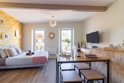 a bedroom with a bed and a table and a kitchen at AU PIED Du Grand Bassin in Castelnaudary