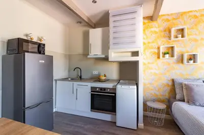 a small kitchen with a refrigerator and a couch at AU PIED Du Grand Bassin in Castelnaudary