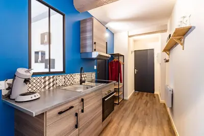 a kitchen with blue walls and a sink and a window at LE COSMO Du Grand Bassin Avec Terrasse in Castelnaudary