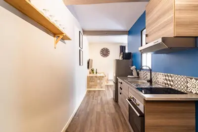 a kitchen with blue walls and wooden flooring at LE COSMO Du Grand Bassin Avec Terrasse in Castelnaudary