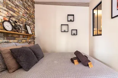 a bedroom with a bed and a brick wall at LE COSMO Du Grand Bassin Avec Terrasse in Castelnaudary