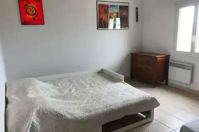 a bedroom with a white bed and a wooden dresser at Maison spacieuse in Gruissan