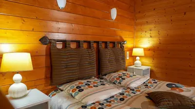 a bedroom with wooden walls and a bed with two lamps at Écolodge Les Sentiers du Lac - Domaine de la Gaïa in Sorèze