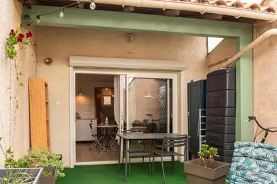 a patio with a table and chairs and a kitchen at gite echarou Chez Nine in Sigean