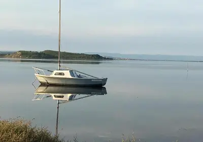 a boat sitting on the water with its reflection at gite echarou Chez Nine in Sigean