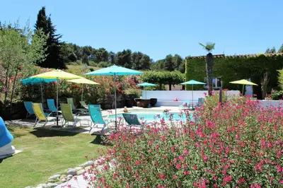 a garden with chairs and umbrellas and a swimming pool at Gîte le Relais de la Cavayere in Carcassonne