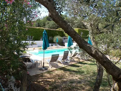 a swimming pool with chairs and umbrellas in a yard at Gîte le Relais de la Cavayere in Carcassonne