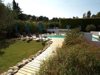 a backyard with a swimming pool with chairs and umbrellas at Gîte le Relais de la Cavayere in Carcassonne