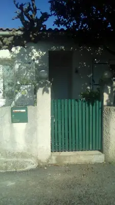 a green door on a house with a fence at Los olivos in Bize-Minervois