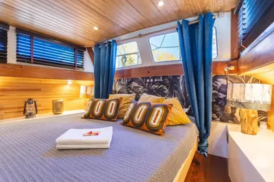 a bed in the center of a boat with blue curtains at Bateau Le Nubian in Narbonne