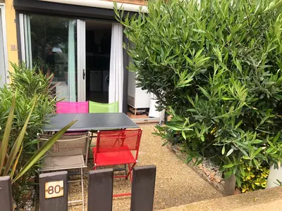 a black table with colorful chairs in a garden at Studio cabine GRUISSAN PLAGE DU GRAZEL in Gruissan