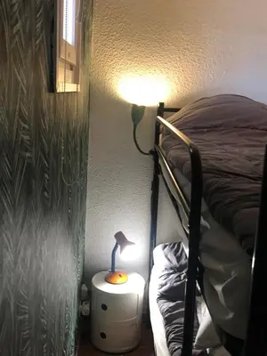 a bedroom with a bed and a lamp on a night stand at Studio cabine GRUISSAN PLAGE DU GRAZEL in Gruissan