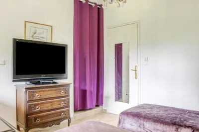a living room with a tv on a dresser and purple curtains at Les Vignes de Carcassonne - Classé 4 étoiles Piscine et clim in Capendu