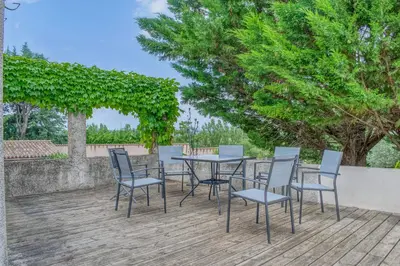 a table and chairs on a wooden deck at Les Vignes de Carcassonne - Classé 4 étoiles Piscine et clim in Capendu