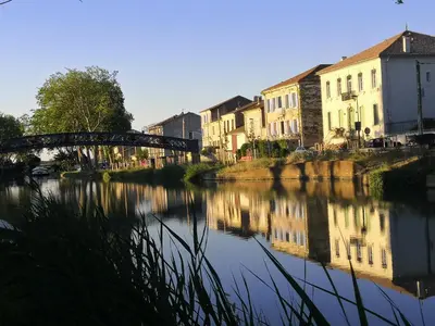 a bridge over a river with houses and buildings at Les Volets Bleus in Sallèles-dʼAude