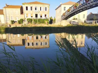 a bridge over a river with buildings in the background at Les Volets Bleus in Sallèles-dʼAude
