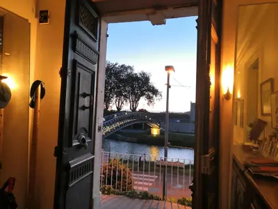an open door with a view of a bridge at Les Volets Bleus in Sallèles-dʼAude