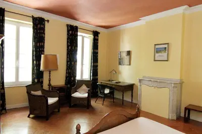 a living room with a desk and chairs and windows at Les Volets Bleus in Sallèles-dʼAude