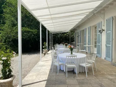 a table with white tables and chairs on a patio at Manoir et Appartements avec piscine au Domaine de Bize Mirepoix in Mirepoix