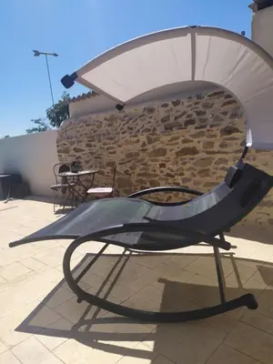 a chair with an umbrella on a patio at Loft au bord du Canal du Midi in Roubia