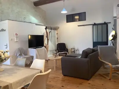 a living room with a couch and a table and chairs at Loft au bord du Canal du Midi in Roubia