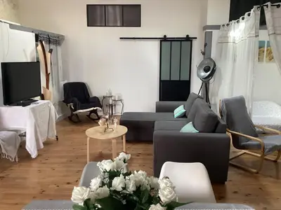 a living room with a couch and a table with flowers at Loft au bord du Canal du Midi in Roubia