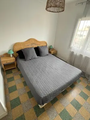 a bed in a bedroom with two night stands and two windows at Maison vivancos in Narbonne