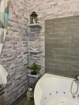 a bathroom with a white tub and a brick wall at restez zen in Carcassonne