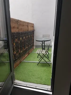 a table and chair on a balcony with green carpet at restez zen in Carcassonne