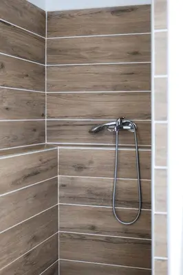 a bathroom with a shower with wood tile at Gîte Esprit Loft Proche de Narbonne in Mirepeisset