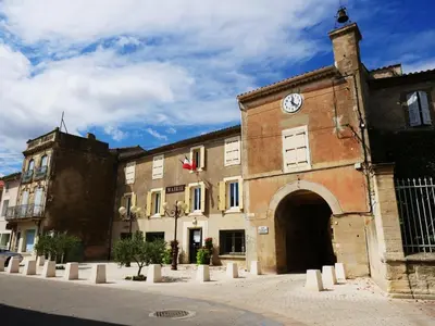 an old building with a clock on the side of it at Gîte Esprit Loft Proche de Narbonne in Mirepeisset