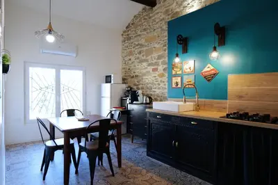 a kitchen with a table and a kitchen with blue walls at Gîte Esprit Loft Proche de Narbonne in Mirepeisset