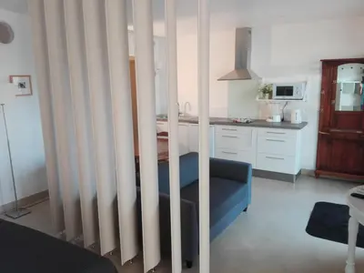 a kitchen with white walls and a blue couch in a room at l-Ostalet in Bages
