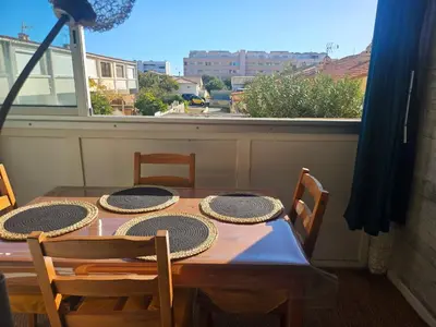 a dining room table with four chairs and a window at PALMA II in Port-la-Nouvelle
