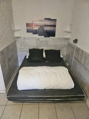 a large bed with white sheets and black pillows at PALMA II in Port-la-Nouvelle