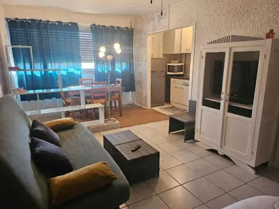 a living room with a couch and a kitchen with a table at PALMA II in Port-la-Nouvelle