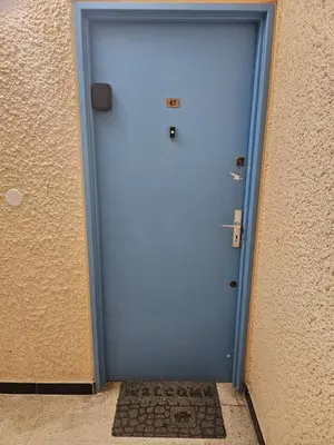 a blue door in a building with a rug in front at PALMA II in Port-la-Nouvelle