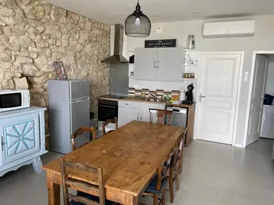a kitchen with a wooden table with chairs and a refrigerator at Parenthèse au bord de l’étang in Bages