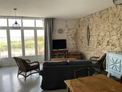 a living room with a couch and a stone wall at Parenthèse au bord de l’étang in Bages