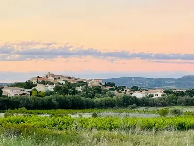 a village on a hill in a field at sunset at Parenthèse au bord de l’étang in Bages