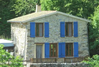 an old stone house with blue shutters on it at Gîtes Le Paradoxe des Pyrénées in Montferrier