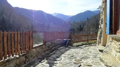 a stone path with a fence and mountains in the background at Gîtes Le Paradoxe des Pyrénées in Montferrier