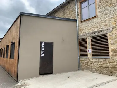 a garage door with a sign on the side of a building at Logis Hotel Nature Cathare in Léran