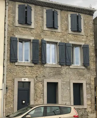 a building with black shuttered windows and a car in front at Coup de cœur 4 étoiles en hyper centre, gare immédiate et canal du midi à 2 pas in Castelnaudary