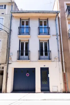 a white building with a black gate and two balconies at Maison La Majorelle - 90m2 - Garage et Terrasse in Pamiers