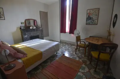 a bedroom with a bed and a table and a fireplace at Maison Mômes in Bize-Minervois