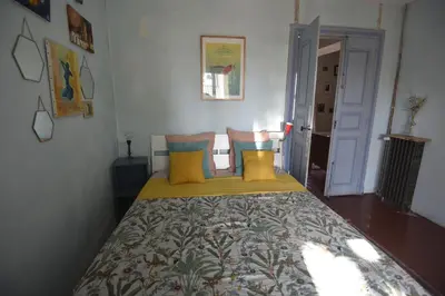 a bed with yellow and blue pillows in a room at Maison Mômes in Bize-Minervois