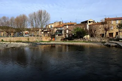 a body of water with buildings in the background at Maison Mômes in Bize-Minervois