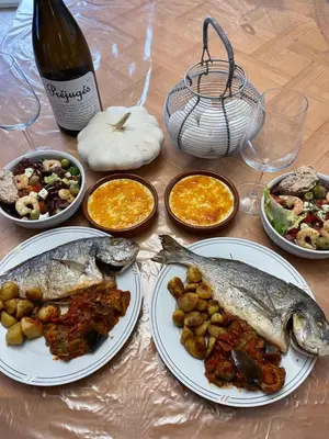 a table with plates of food and a bottle of wine at Chez Tatie Ménie in Fraissé-des-Corbières