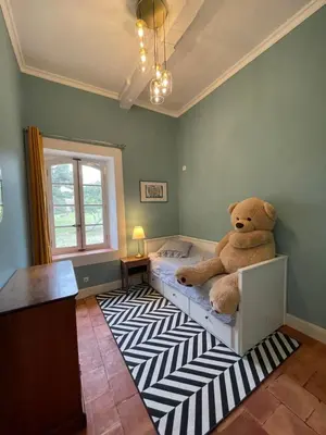 a teddy bear sitting on a bed in a bedroom at Maison Saraphina in Cruzy